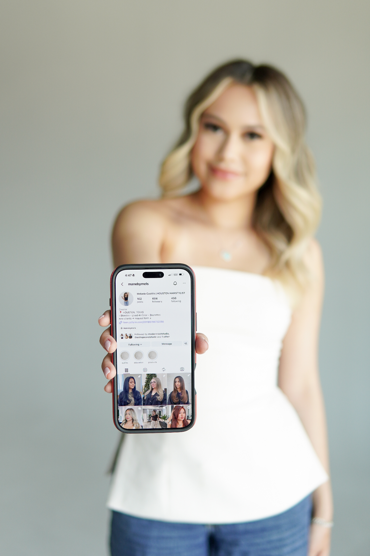 Melanie holding her phone showing the ManebyMels Instagram profile